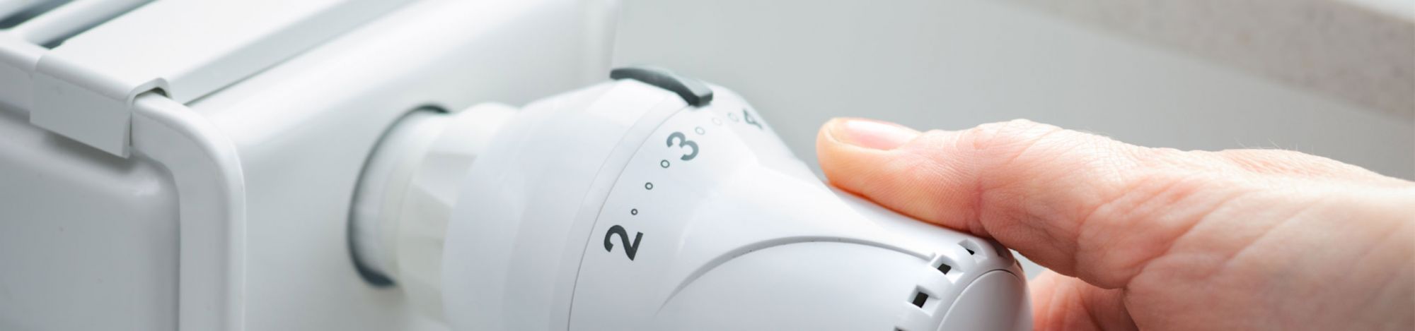 Hand an einem Heizungsthermostat
