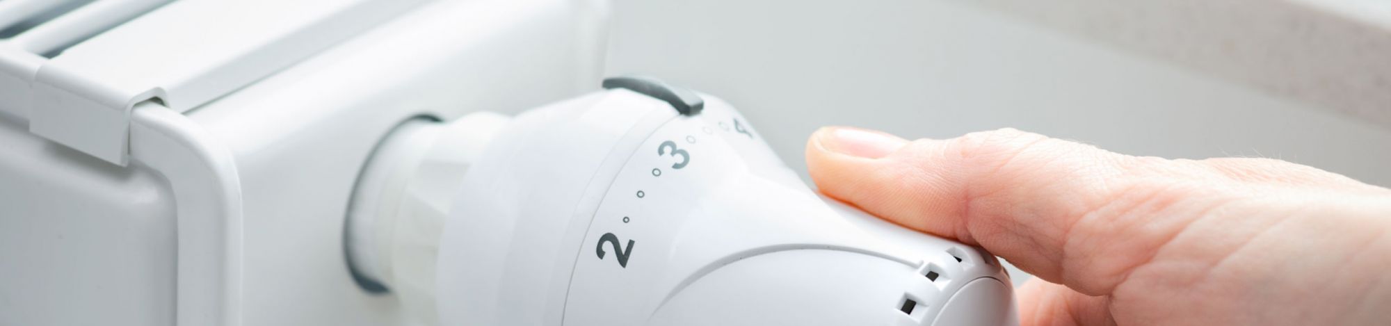Hand, die ein Thermostat bedient. 