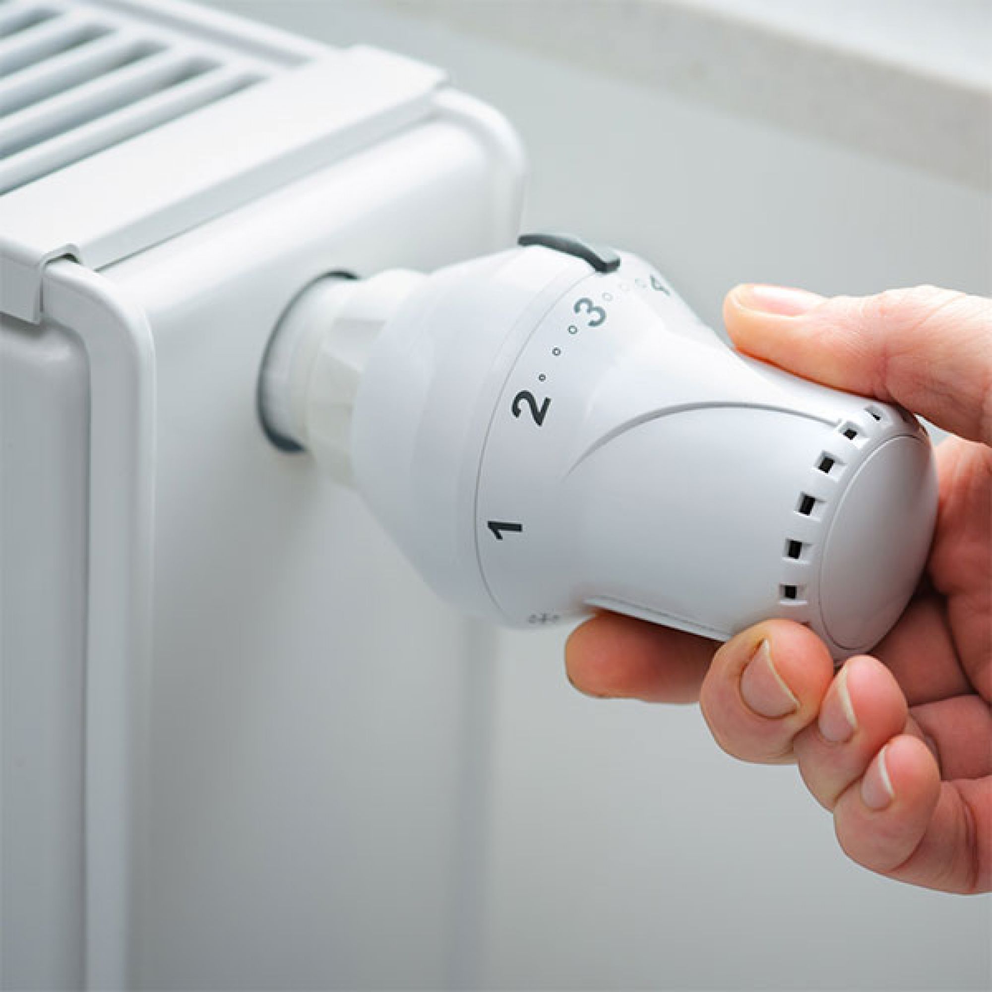 Hand an einem Heizungsthermostat